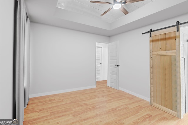 149 Irwin St, Cedartown, GA 30125 - unfurnished bedroom featuring a tray ceiling, wood finished floors, a barn door, and baseboards
