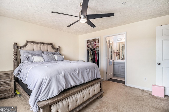 bedroom with a closet, light carpet, a spacious closet, a textured ceiling, and ensuite bathroom