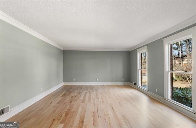 3672 Howell Wood Trl NW, Duluth, GA 30096 - spare room featuring visible vents, baseboards, light wood finished floors, ornamental molding, and a textured ceiling