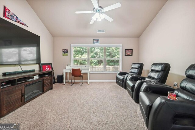 home theater room with a ceiling fan, light carpet, vaulted ceiling, and visible vents