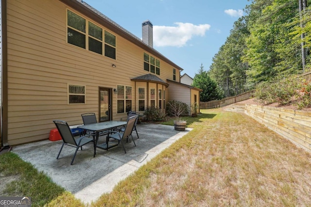 back of property with a lawn, fence, a chimney, and a patio area