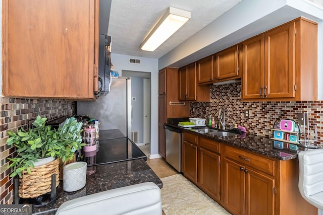 909 Glenleaf Dr, Peachtree Corners, GA 30092 - kitchen with a sink, appliances with stainless steel finishes, brown cabinets, dark stone counters, and light tile patterned floors