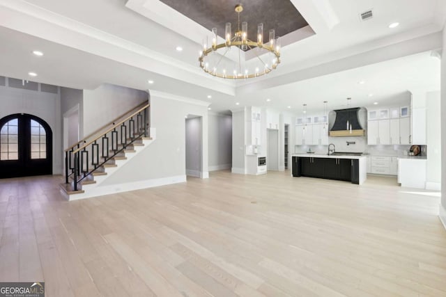 3057 Bold Springs Rd, Dacula, GA 30019 - unfurnished living room with a tray ceiling, a notable chandelier, stairs, and light wood finished floors
