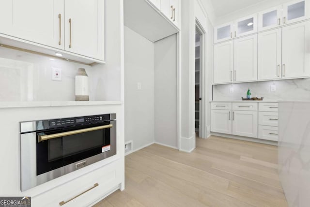 3057 Bold Springs Rd, Dacula, GA 30019 - kitchen featuring light wood-type flooring, oven, light countertops, white cabinetry, and glass insert cabinets