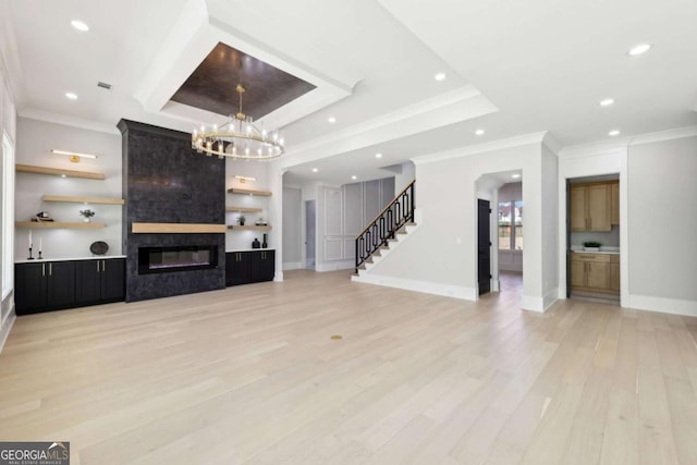 3057 Bold Springs Rd, Dacula, GA 30019 - unfurnished living room featuring light wood-style flooring, a chandelier, stairway, crown molding, and a fireplace