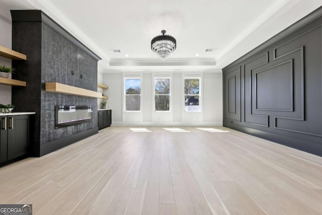 3057 Bold Springs Rd, Dacula, GA 30019 - unfurnished living room with light wood finished floors, visible vents, a large fireplace, a tray ceiling, and an inviting chandelier
