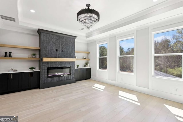 3057 Bold Springs Rd, Dacula, GA 30019 - unfurnished living room with a tray ceiling, crown molding, light wood-style flooring, a chandelier, and a fireplace