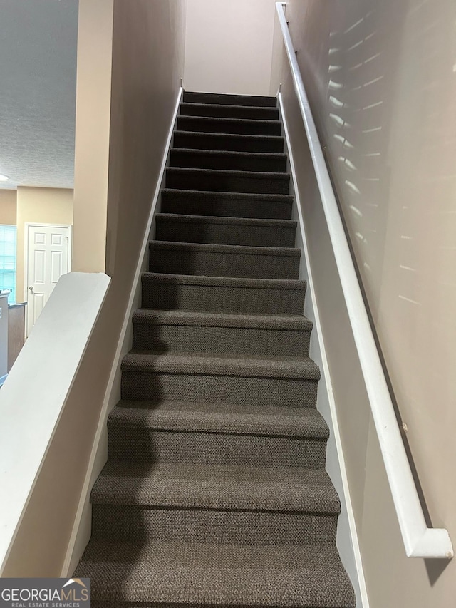 stairs featuring a textured ceiling