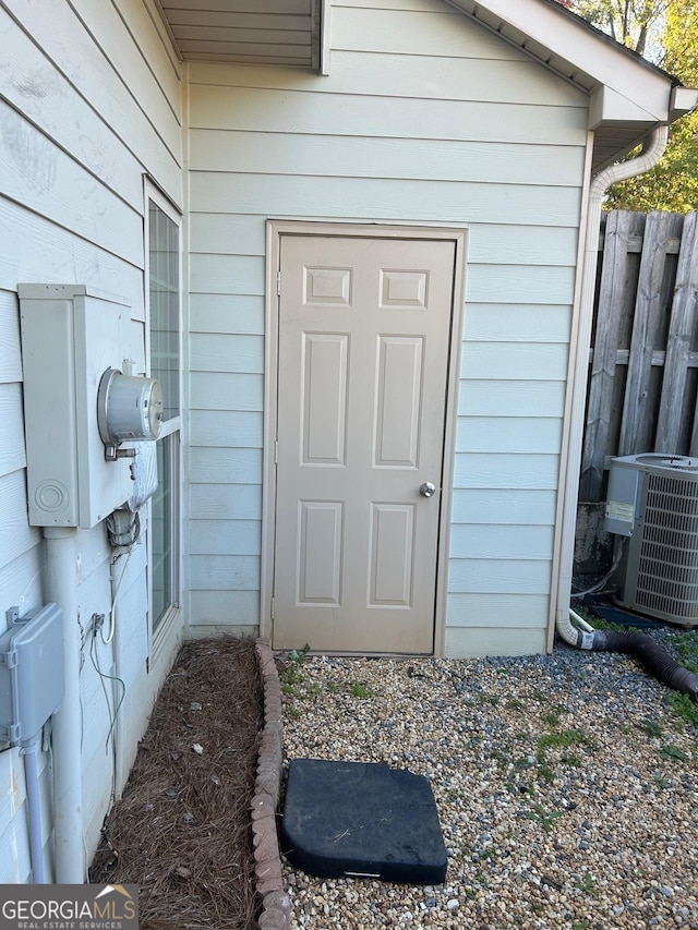 entrance to property featuring central AC unit and fence