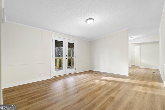 empty room with a textured ceiling, wood finished floors, french doors, crown molding, and baseboards