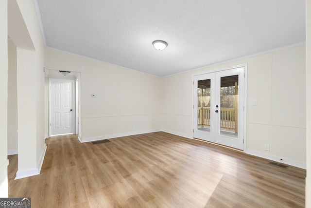 empty room with light wood-type flooring, visible vents, a textured ceiling, french doors, and baseboards