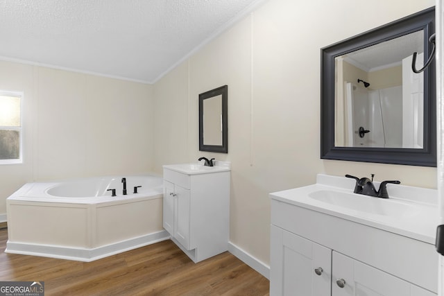 full bath with crown molding, a garden tub, two vanities, wood finished floors, and a sink