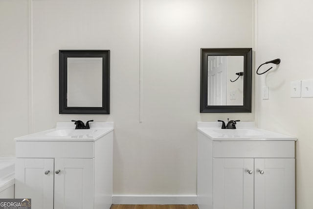 full bathroom with two vanities, baseboards, and a sink