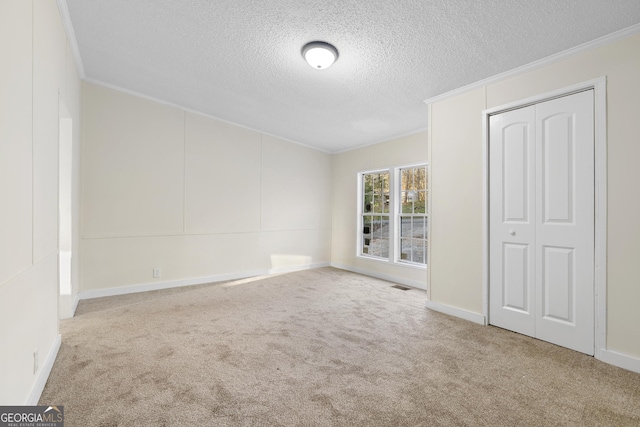 interior space with visible vents, carpet floors, ornamental molding, a closet, and a textured ceiling