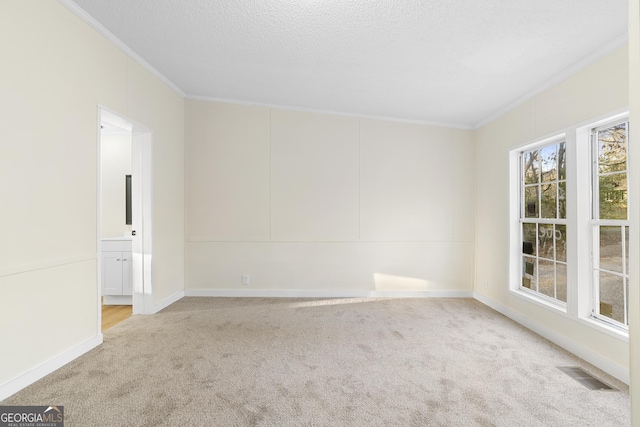 empty room featuring crown molding, carpet flooring, visible vents, and a textured ceiling