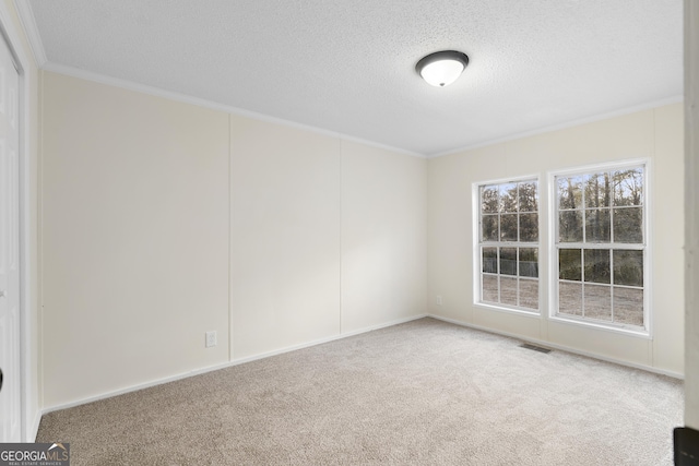 carpeted spare room with visible vents, a textured ceiling, and ornamental molding