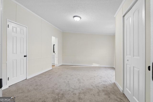 unfurnished bedroom featuring ensuite bathroom, a textured ceiling, carpet flooring, and crown molding