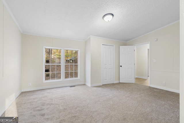 unfurnished room with baseboards, a textured ceiling, carpet flooring, and crown molding