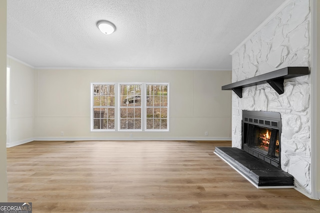 unfurnished living room with crown molding, a fireplace, light wood-style floors, and a textured ceiling