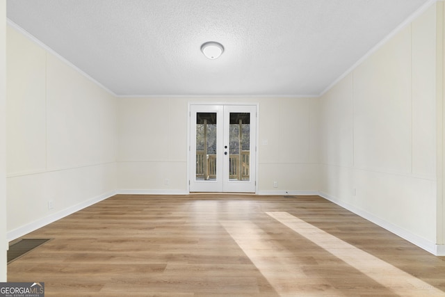 spare room with crown molding, french doors, light wood finished floors, and a textured ceiling