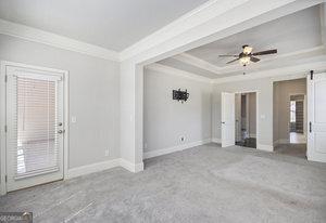 carpeted spare room featuring baseboards, a barn door, ceiling fan, crown molding, and a raised ceiling