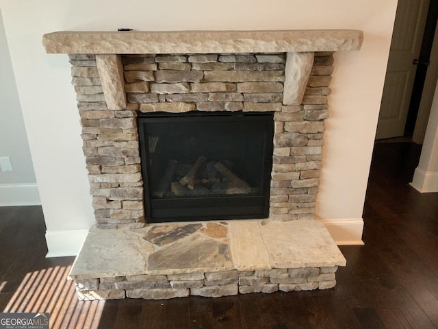 interior details with a stone fireplace, wood finished floors, and baseboards