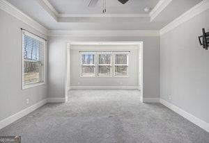 unfurnished room featuring a raised ceiling, carpet floors, and crown molding