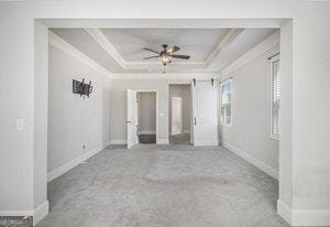 spare room with ceiling fan, a raised ceiling, baseboards, and ornamental molding