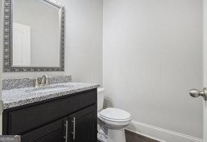half bath with toilet, vanity, and baseboards