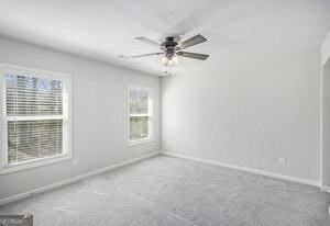 carpeted spare room with baseboards and ceiling fan