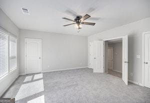 unfurnished bedroom featuring carpet flooring, baseboards, visible vents, and ceiling fan