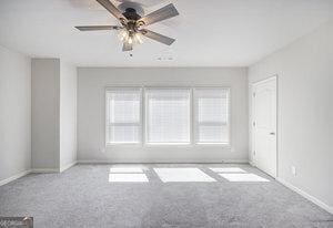 carpeted empty room featuring a healthy amount of sunlight, baseboards, and ceiling fan
