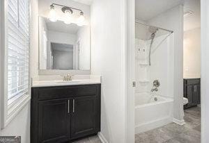 bathroom featuring shower / bath combination, baseboards, and vanity