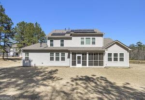 rear view of house featuring roof mounted solar panels