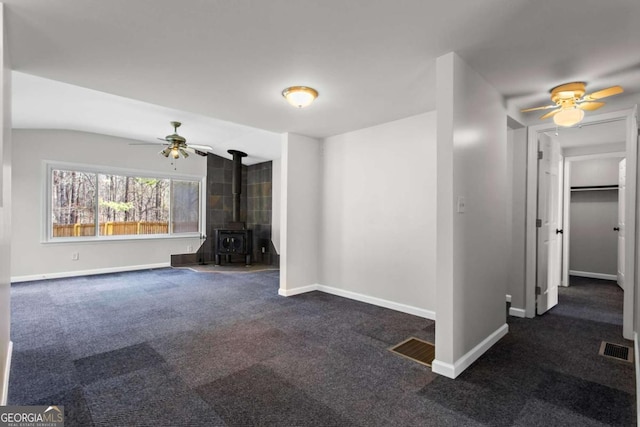 1833 Lost Mountain Rd, Powder Springs, GA 30127 - unfurnished living room featuring a ceiling fan, visible vents, baseboards, a wood stove, and dark carpet