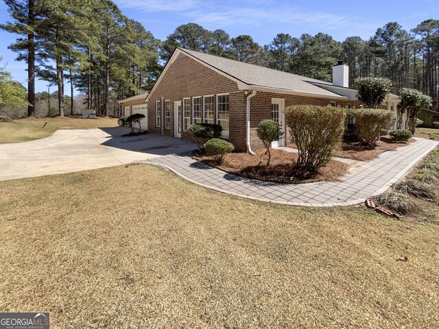 105 Creekwood Ln, Fayetteville, GA 30214 - view of home's exterior with driveway, a yard, a garage, brick siding, and a chimney