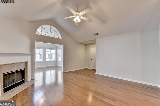 unfurnished living room with light wood finished floors, visible vents, baseboards, a tiled fireplace, and a ceiling fan