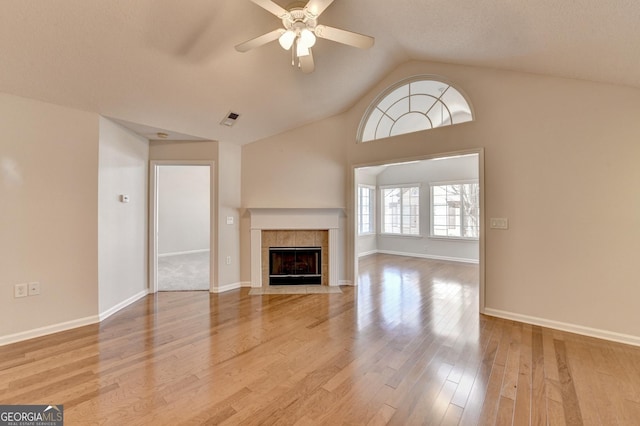 unfurnished living room featuring visible vents, a ceiling fan, light wood finished floors, vaulted ceiling, and a tile fireplace