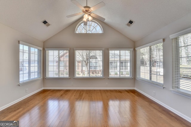 unfurnished sunroom with a textured ceiling, wood finished floors, visible vents, and baseboards