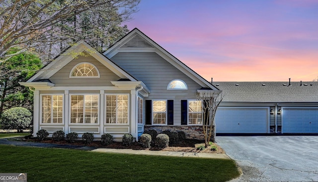 view of front facade with aphalt driveway, a garage, stone siding, and a front yard