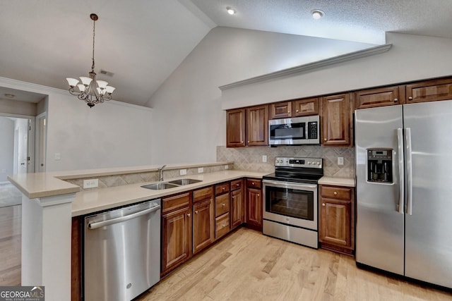 kitchen featuring a peninsula, stainless steel appliances, light countertops, and a sink