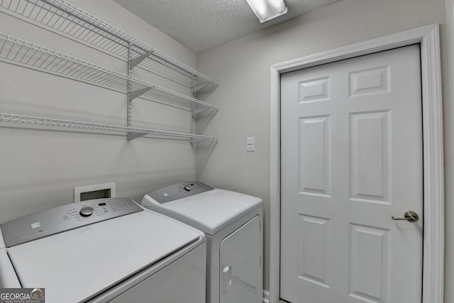 clothes washing area with laundry area, washer and dryer, and a textured ceiling