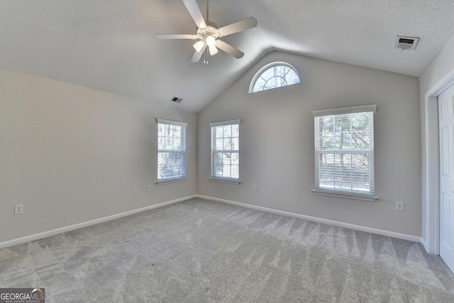 spare room featuring visible vents, ceiling fan, vaulted ceiling, carpet floors, and a textured ceiling