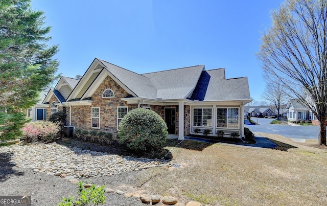 view of front facade with stone siding and a shingled roof