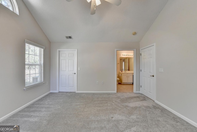 unfurnished bedroom featuring visible vents, light carpet, a ceiling fan, ensuite bathroom, and baseboards