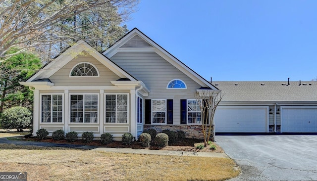 view of front facade with stone siding, driveway, and an attached garage