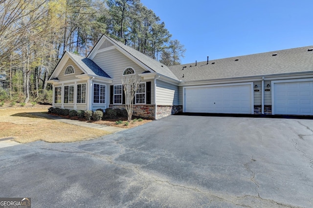 view of front of house with a garage, stone siding, driveway, and a shingled roof
