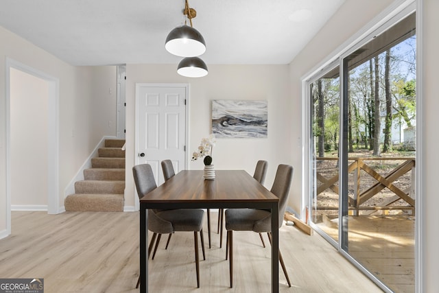 dining space with stairway, light wood-style floors, and baseboards