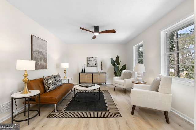 living room featuring baseboards, a ceiling fan, and wood finished floors