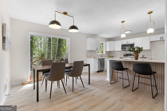 dining space featuring visible vents, light wood-style flooring, and baseboards